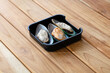 fresh raw mussels sliced on square plate isolated on wooden background, shabu, hot pot ingredients