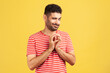 © khosrork - Sneaky cunful man with beard in striped red t-shirt drumming fingers planning devious pranks, thinking over revenge plan, scheming. Indoor studio shot isolated on yellow background