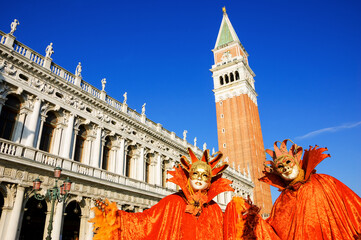 Two orange optimistic masks at St Mark's Square during traditional Carnival. Venice, Italy. Positive energy, happiness concepts.