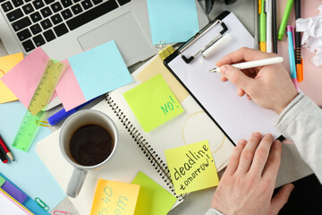 Wall Mural - Man writing at messy table, top view. Concept of being overwhelmed by work