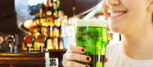 Alcohol Drinks And St Patrick's Day Concept - Close Up Of Woman With Green Beer In Glass Over Bar Background