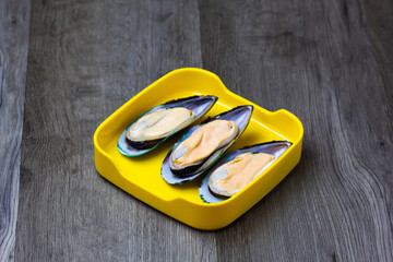 Wall Mural - fresh mussels sliced on square plate  on wood, wooden background,set shabu, hot pot ingredients.