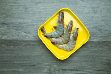 Wall Mural - fresh raw shrimp sliced on square plate  on wood, wooden background,set shabu, hot pot ingredients.