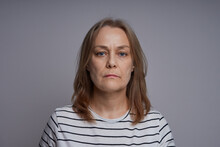 Close Up Portrait Of Serious Middle Aged Woman. Studio Shot Over Gray Background.