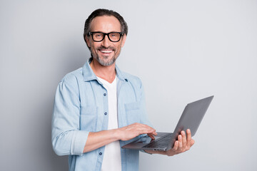 Photo of mature man happy positive smile programmer work online type browse laptop isolated over grey color background