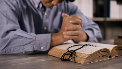 Wall Mural - A young Asian Christian man praying to Jesus Christ in a church.