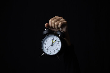 Human hand holding alarm clock in the dark, Copy space.