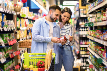 smiling couple with the cart choosing products in supermarket