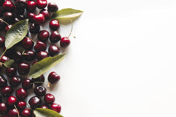 Wall Mural - Fresh ripe cherry with green leaves on the white wooden background. Top view, copy space