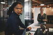 © Flamingo Images - Smiling young businessman sitting at a table during a presentation