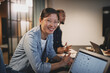 © Flamingo Images - Smiling young Asian businesswoman sitting with colleagues around a table