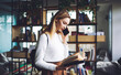 © BullRun - Woman speaking on phone while studying book in library