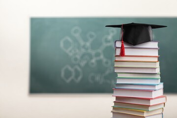 Wall Mural - Stack school books with a black graduation hat