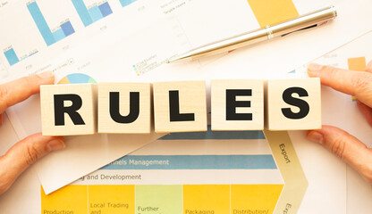 Cropped view of hands holding wooden cubes with RULES lettering on work table.