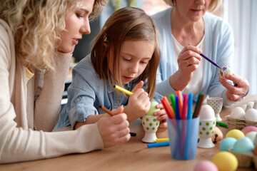 Three generations of women during painting Easter eggs at home