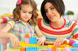 © aletia2011 - Cute little girl and her mother playing colorful plastic blocks together in her room