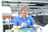 Fototapeta  - friendly woman working in a microelectronics manufacturing factory - component assembly and soldering