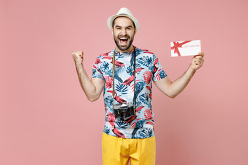 Wall Mural - Happy young traveler tourist man in summer basic clothes hat hold gift certificate doing winner gesture isolated on pink background studio. Passenger traveling on weekends. Air flight journey concept.