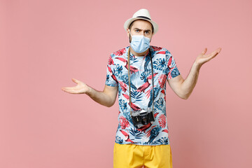 Wall Mural - Worried young traveler tourist man in face mask to safe from coronavirus virus covid-19 spreading hands isolated on pink background studio. Passenger traveling on weekends. Air flight journey concept.