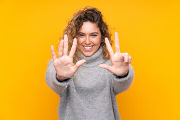 Wall Mural - Young blonde woman with curly hair wearing a turtleneck sweater isolated on yellow background counting eight with fingers