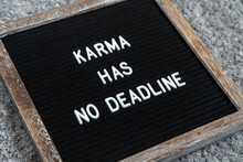 Felt Letter Board Sign "Karma Has No Deadline" In A Wooden Frame On Black Background. Closeup.