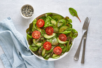 Wall Mural - Vegan salad with tomatoes, cucumbers, avocado on pastel gray concrete table. Vegeterian mediterranean food, low calories dieting meal