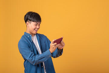 Happy Asian man watch their phone horizontally On orange background