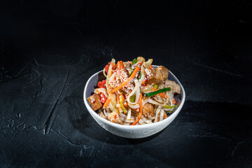 Wall Mural - Udon stir-fry noodles with chicken and vegetables on dark background. Appetizing asian cuisine