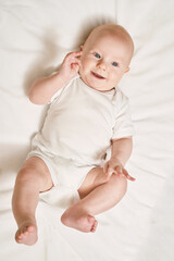 cute small boy lying at bed. childhood concept. light background. smiling child. happy emotion. copy