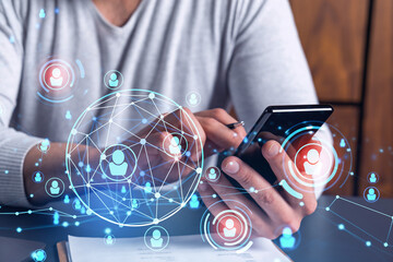 Hands of hr specialist browsing social networks in the Internet in smart phone to find the best candidates to hire international team. Concept of success. Media hologram icons.