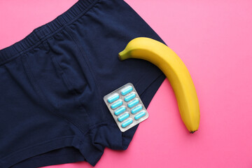 Wall Mural - Men's underwear, pills and banana on pink background, flat lay. Potency problem concept