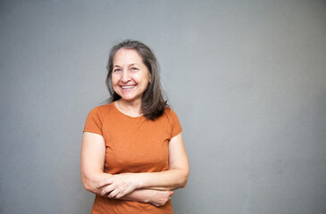 Wall Mural - Senior woman in  brown t-shirt studio isolated on grey wall