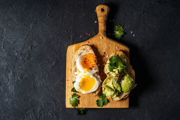 Wall Mural - Poached egg and avocado on sliced toasted bread, top view