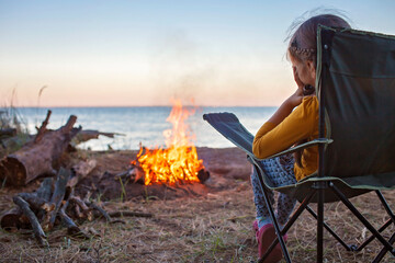 family local getaway. kid sitting on the touristic armchair and looking at fire before overnight at 