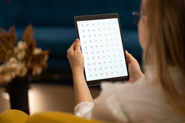Women with cute glasses reading e-book, watching news, browsing internet. Home office. Shot over shoulder.