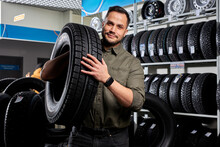 Customer Tire Fitting In The Car Service, Auto Mechanic Checks The Tire And Rubber Tread For Safety, Concept: Repair Of Machines, Fault Diagnosis, Repair. Man Buy In Car Service Shop