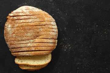 Sliced homemade sourdough rye bread with rye flour on black textured background. Top view or flat-lay. Low key