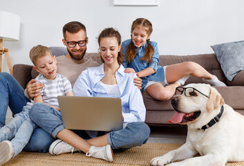 Happy parents with kids and dog watching movie on laptop