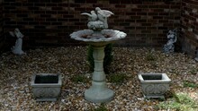 Bird Bath And Statue With Concrete Flower Pots In River Rocks