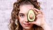 young cute girl closes her eye with avocado,  healthy eating