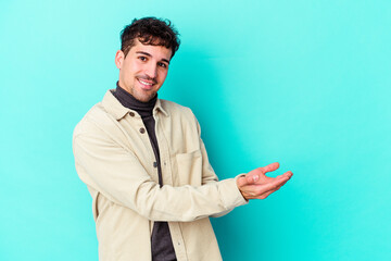 Wall Mural - Young caucasian man isolated on blue background holding a copy space on a palm.