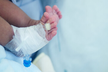 Wall Mural - newborn baby's leg wrapped in a cotton swab and a needle for medication.