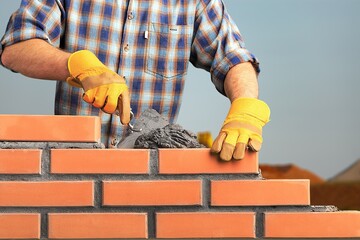 Wall Mural - Bricklayer worker installing brick masonry