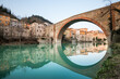 Wide angle view of the Devil's bridge in Fossombrone, mirrored on still water