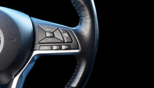 Part Of Modern Steering Wheel Isolated On Black Background. Steering Wheel With Media, Phone And Cruise Control Buttons Isolated On Black Background. Car Interior Details. Car Inside