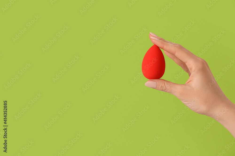 Hand with makeup sponge on color background