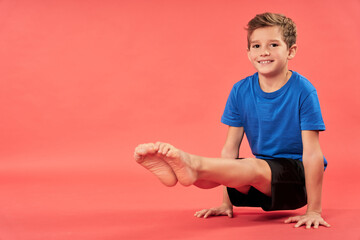 cheerful boy doing exercise against red background
