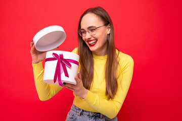 Happy young woman with a white gift box on a red background