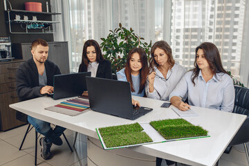 Friendly team of engineers thinking on a project and working together in their office looking at a laptop and taking notes in a notebook. Working day concept