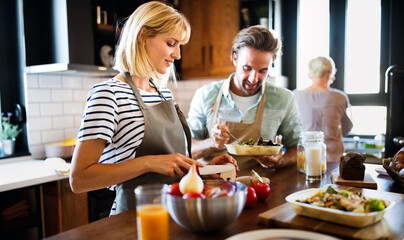 Wall Mural - Portrait of happy young couple cooking together in the kitchen at home.